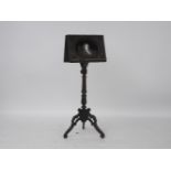 A black forest carved double side music stand, the front with a reverse painted portrait of