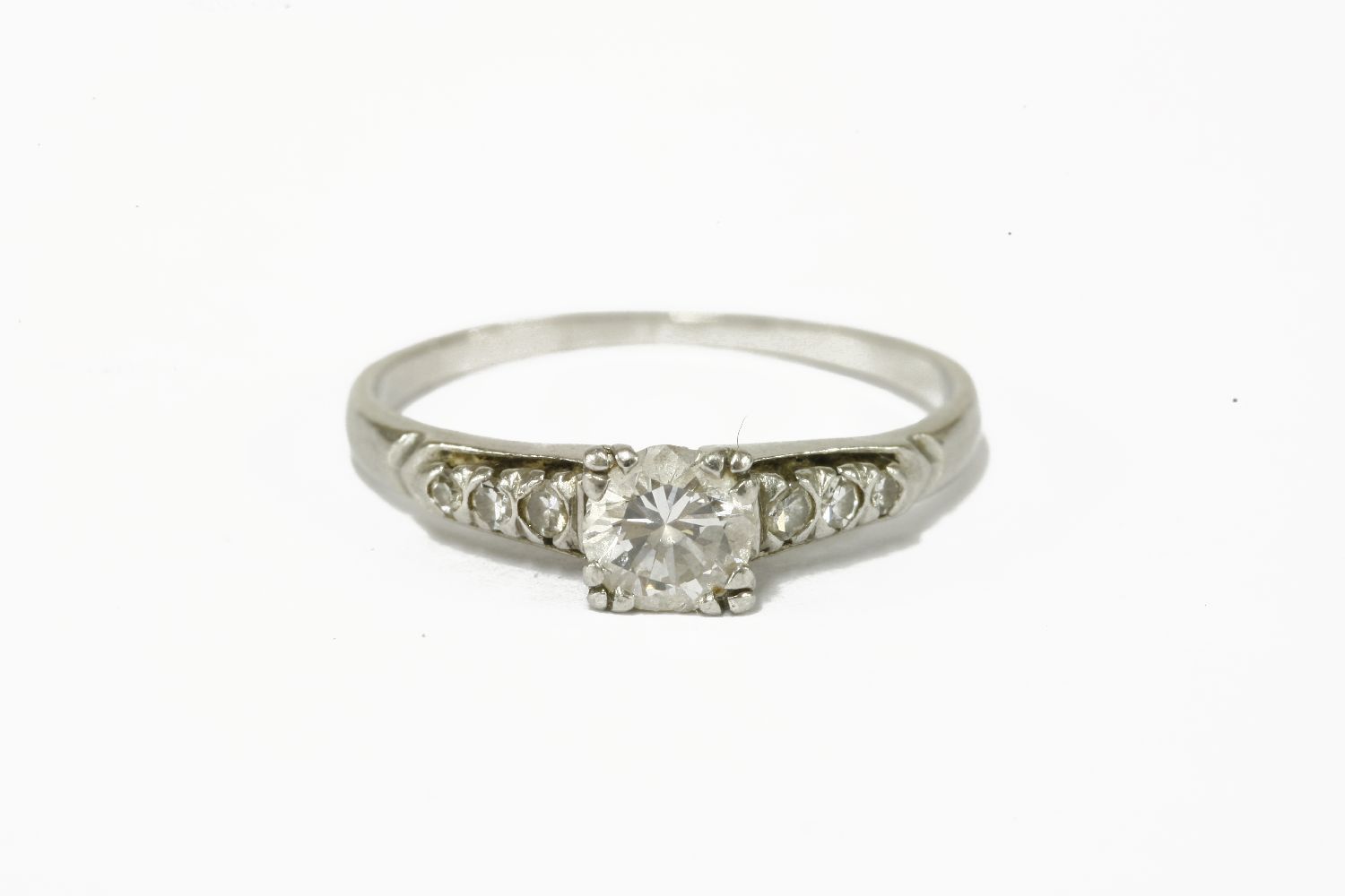 A single stone diamond ring, double claw set to a square collet, with three graduated diamonds on