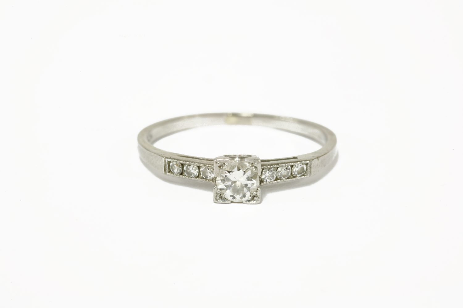 A single stone diamond ring with six brilliant cut diamonds to shoulders, marked 10% irid.