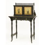 An Aesthetic ebonised writing desk, the painted cupboards centred with lilies in a vase, opening