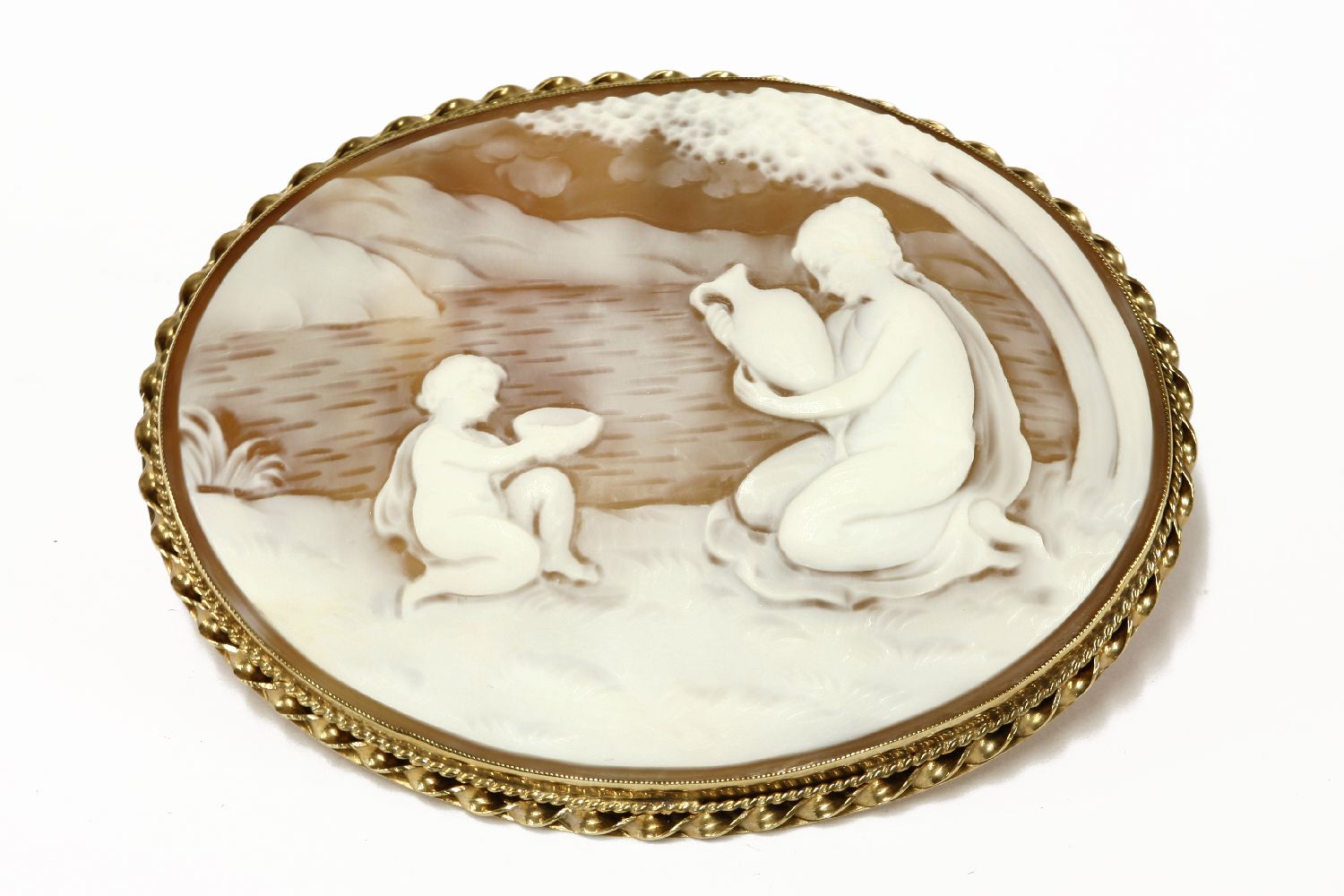 A 9ct gold mounted shell cameo brooch of a young maiden in a landscape setting