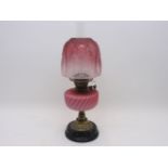 A Victorian brass oil lamp with enamel sunburst levers, having a graduated raspberry glass