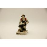 An early 19th century Staffordshire figure of a cobbler, seated, mending a shoe, his dog peeping out