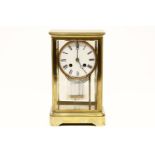 An early 20th century brass and four glass mantel clock, with white enamel dial and black Roman
