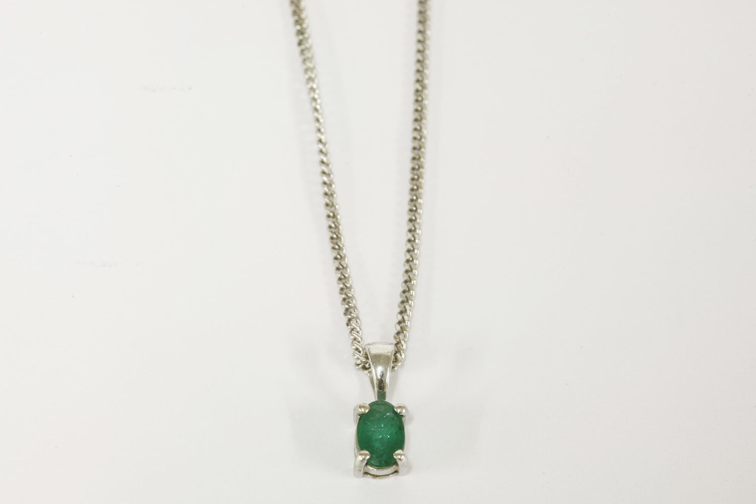 An 18ct white gold single stone oval cut emerald pendant, on an 18ct gold curb link chain