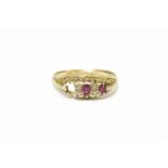 An 18ct gold three stone ruby ring, set with four diamond points (one stone deficient)2.82g