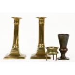 Four metal items: a cup, a brass magnifying glass and a pair of Georgian brass candlesticks. 17.