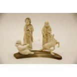 Two Japanese Meiji period ivory figures, and an Inuit carved ivory figure group