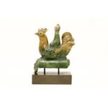 A 19th century Chinese pottery figural ridge tile in the form of a man riding on a cockerel,