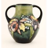 A Moorcroft two-handled vase,c.1935, decorated with a bunch of irises and exotic flowers, on a