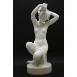 A large Herend white figure of a girl sitting adjusting her hair, base inscribed and with