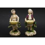 A pair of Derby figures of gardeners,both male and female figures carry a basket, standing on bocage