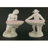 A pair of Royal Worcester figural bonbon dishes,a boy and girl with outstretched hands, holding a