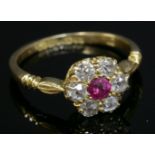 An 18ct gold Edwardian ruby and diamond daisy cluster ring,with a circular mixed cut ruby claw set