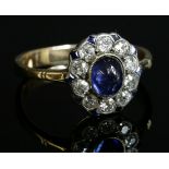 A sapphire and diamond oval cluster ring,with an oval cabochon sapphire, milligrain set to the