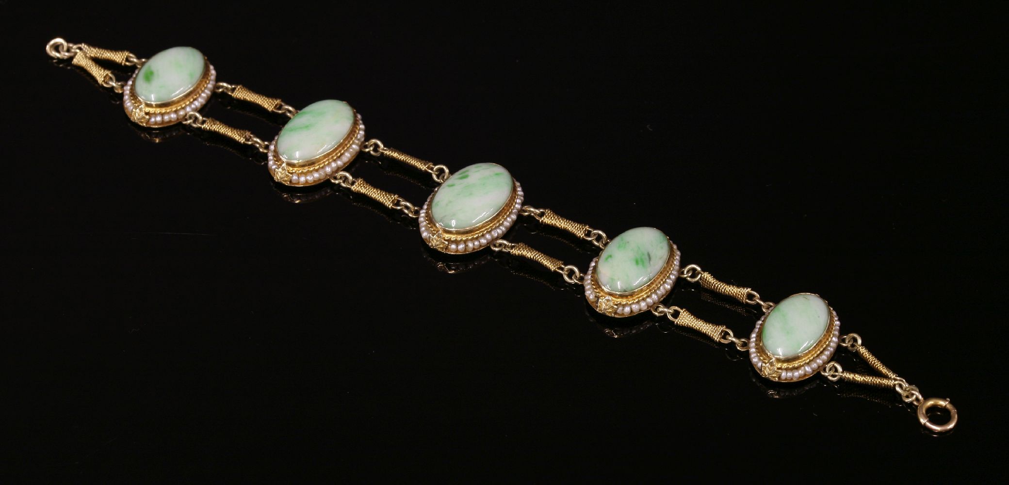 An American jade and seed pearl bracelet,with five graduated oval jade cabochons, each one rub set