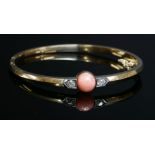 An Edwardian coral and diamond set hinged gold bangle, c.1910,an 8mm bouton coral bead, peg set to