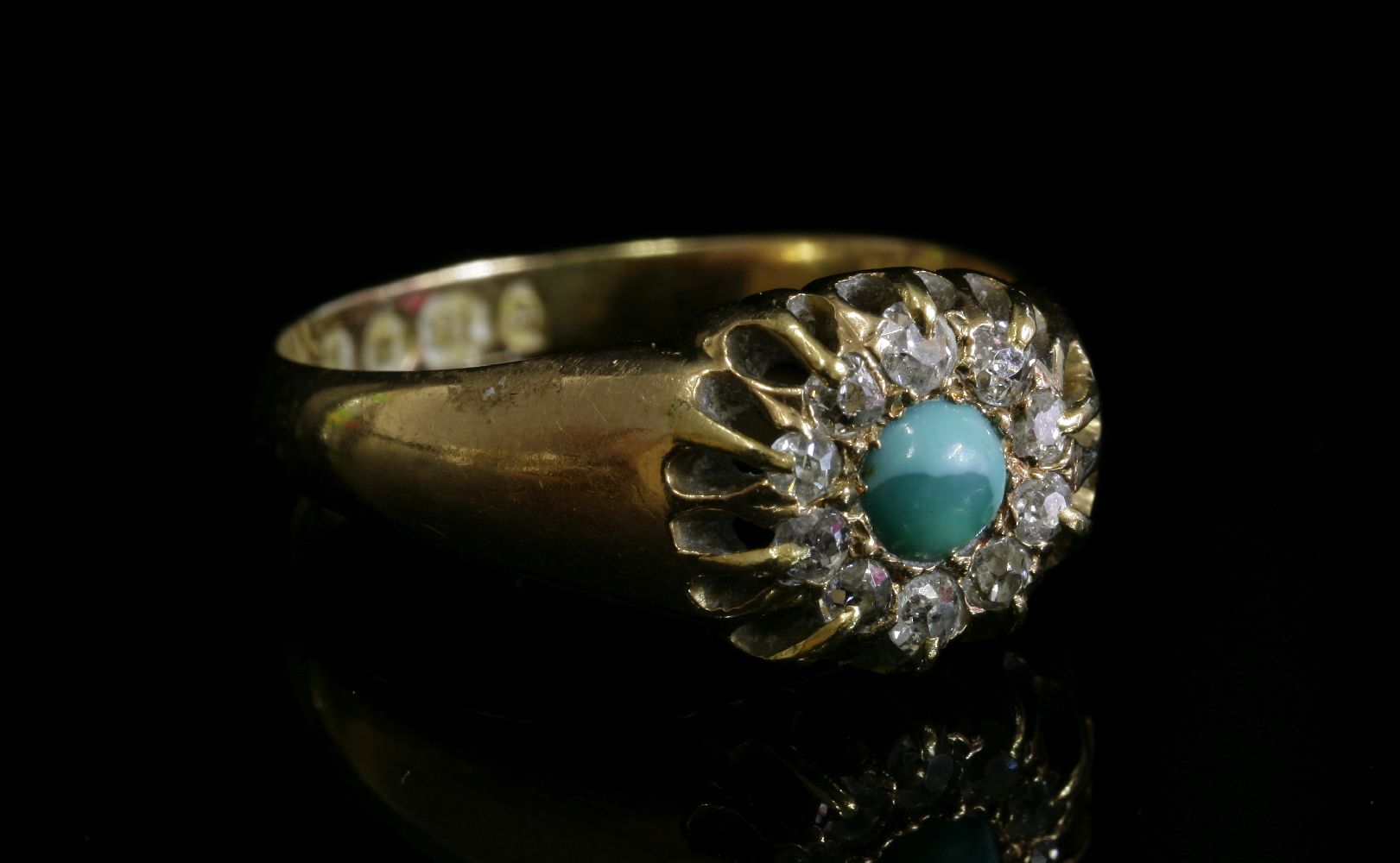 A late Victorian turquoise and diamond cluster ring,with a circular cabochon turquoise, grain set