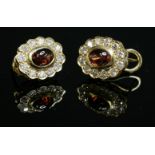 A pair of gold garnet and diamond cluster earrings,with an oval cabochon garnet rub set to the