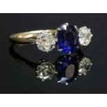 A two colour gold, sapphire and diamond three stone ring,with an oval mixed cut sapphire, claw set