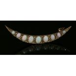An Edwardian opal and diamond crescent brooch, c.1910,with a curved row of graduated oval cabochon