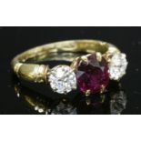 An 18ct gold Edwardian three stone ruby and diamond ring, with a circular mixed cut ruby,claw set to