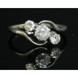 A three stone graduated diamond crossover ring,with an old brilliant cut diamond, claw set in a