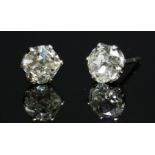 A pair of single stone diamond stud earrings,with two old cushion cut diamonds, claw set to white