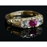 An Edwardian three stone ruby and diamond carved head ring,with a central circular mixed cut ruby