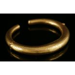 A gold, graduated, hollow, round section torque bangle,by Ilias Lalaounis, with two hinged