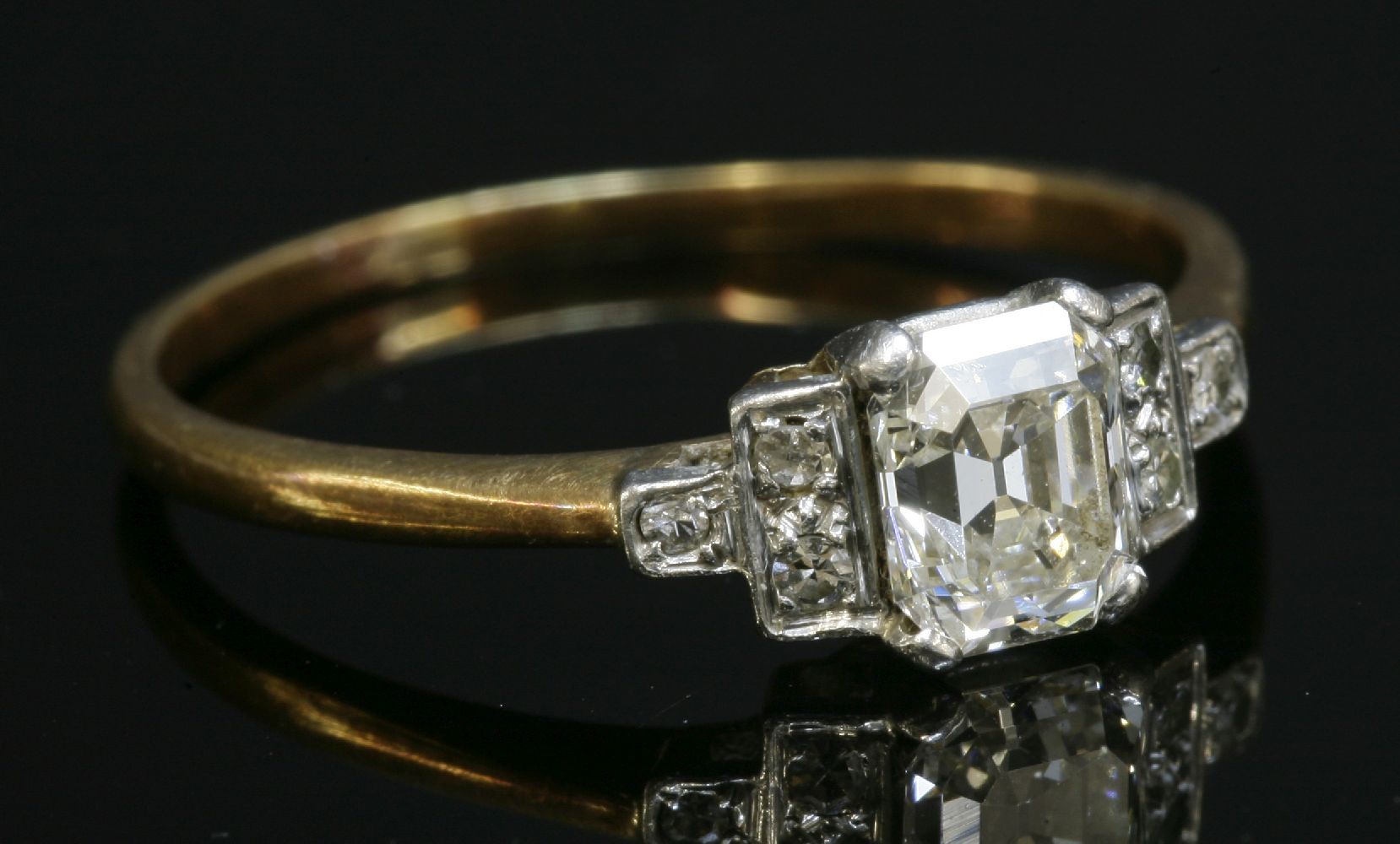 An Art Deco single stone diamond ring, with diamond set shoulders, with an emerald cut diamond,