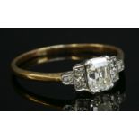 An Art Deco single stone diamond ring, with diamond set shoulders, with an emerald cut diamond,