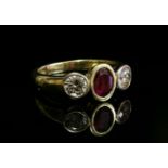 An 18ct gold, ruby and diamond three stone ring,with an oval mixed cut ruby, rub set to the centre
