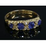 An 18ct gold Edwardian four stone sapphire and diamond carved head ring,with four graduated oval