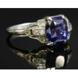 An Art Deco synthetic sapphire ring,with strapwork-style diamond set shoulders. A cushion-shaped