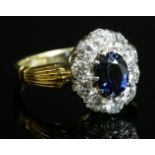 An 18ct gold sapphire and diamond oval cluster ring,with an oval mixed cut sapphire, claw set to the