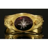 A Victorian gold garnet and diamond hinged bangle,with a central oval cabochon garnet with applied