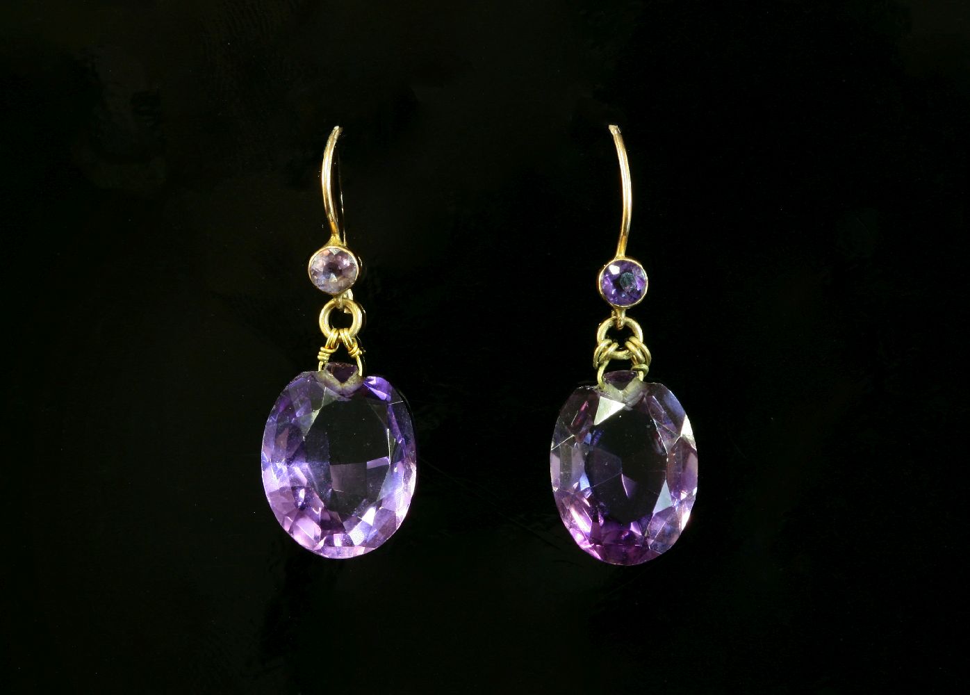 A pair of Edwardian amethyst drop earrings,with a circular mixed cut amethyst, rub set in a plain