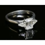 A platinum three stone diamond ring,with a central emerald cut diamond with a known weight of 0.