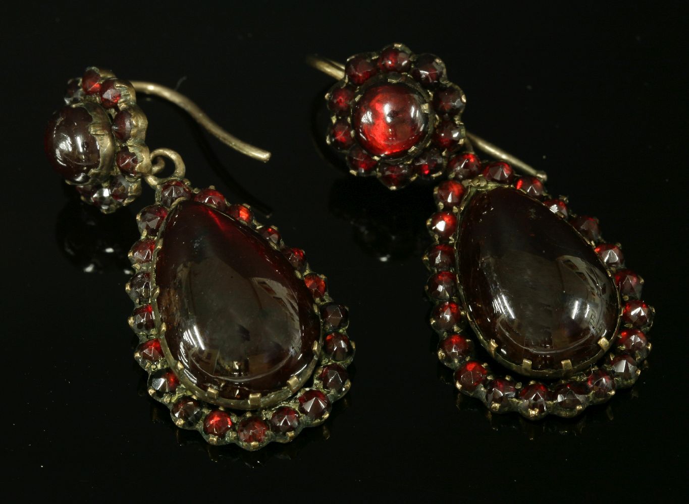 A pair of Victorian Bohemian gilt metal garnet drop earrings,composed of a circular cabochon garnet,