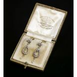 A pair of cased Edwardian diamond drop earrings,with a fleur-de-lys top, milligrain set with