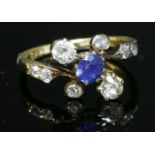 An Art Nouveau sapphire and diamond crossover ring with an oval mixed cut sapphire,claw set to the