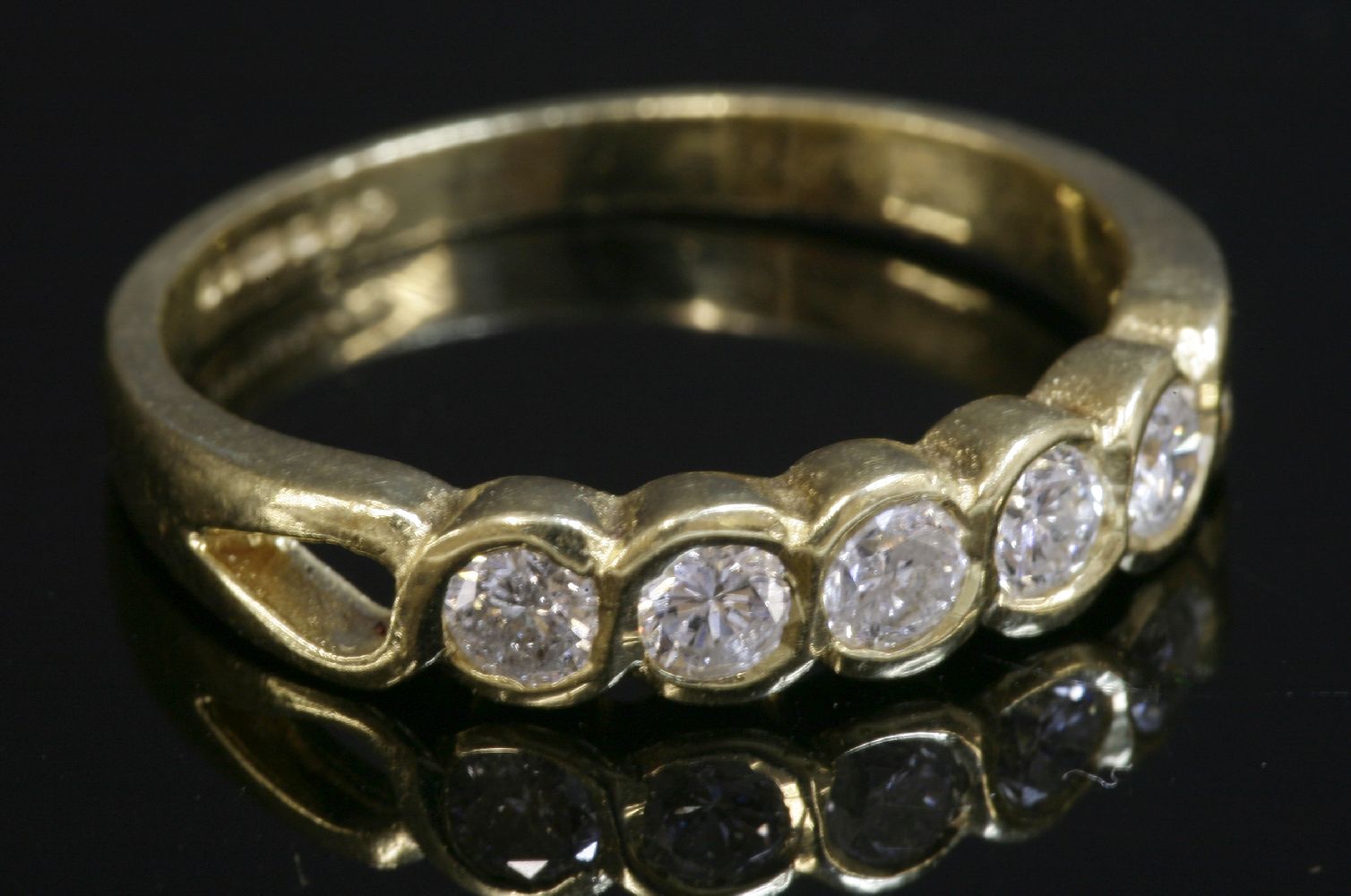 An 18ct gold diamond set half eternity ring, with five brilliant cut diamonds, rub set in 'S' shaped