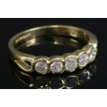 An 18ct gold diamond set half eternity ring, with five brilliant cut diamonds, rub set in 'S' shaped