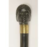 An ebonised walking stick,early 20th century(?), carved with an African head, the shaft unscrewing