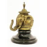 An unusual brass inkwell, modelled as an elephant's head, with a pottery liner, on a glazed