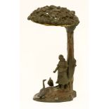 A patinated bronze night light, modelled as a lady feeding geese beneath a tree, an owl seated at