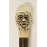 A rosewood walking stick,early 20th century(?), carved with an ivory automaton monkey's head, his