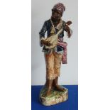 A late 19th century hand-decorated Continental Majolica glazed Blackamoor Figure playing a lute,