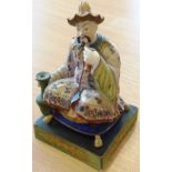 A 19th century Continental hand-decorated porcelain Figure of a Chinaman seated upon a gilt